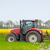 Abb. Ein Traktor fährt auf einer Wiese